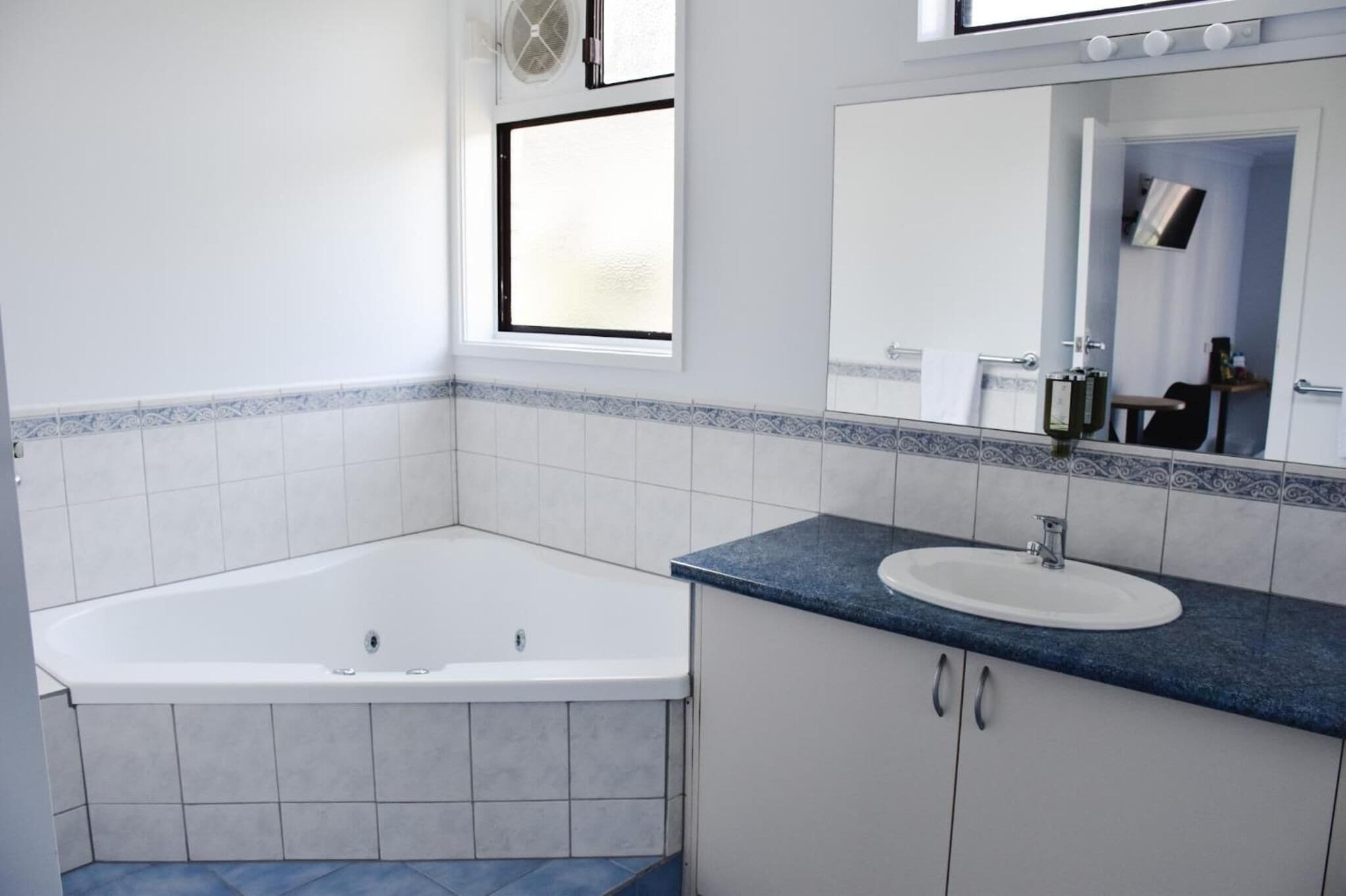 A bathroom with a bathtub, a sink, and a mirror.