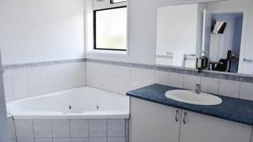 A bathroom with a bathtub, a sink, and a mirror.