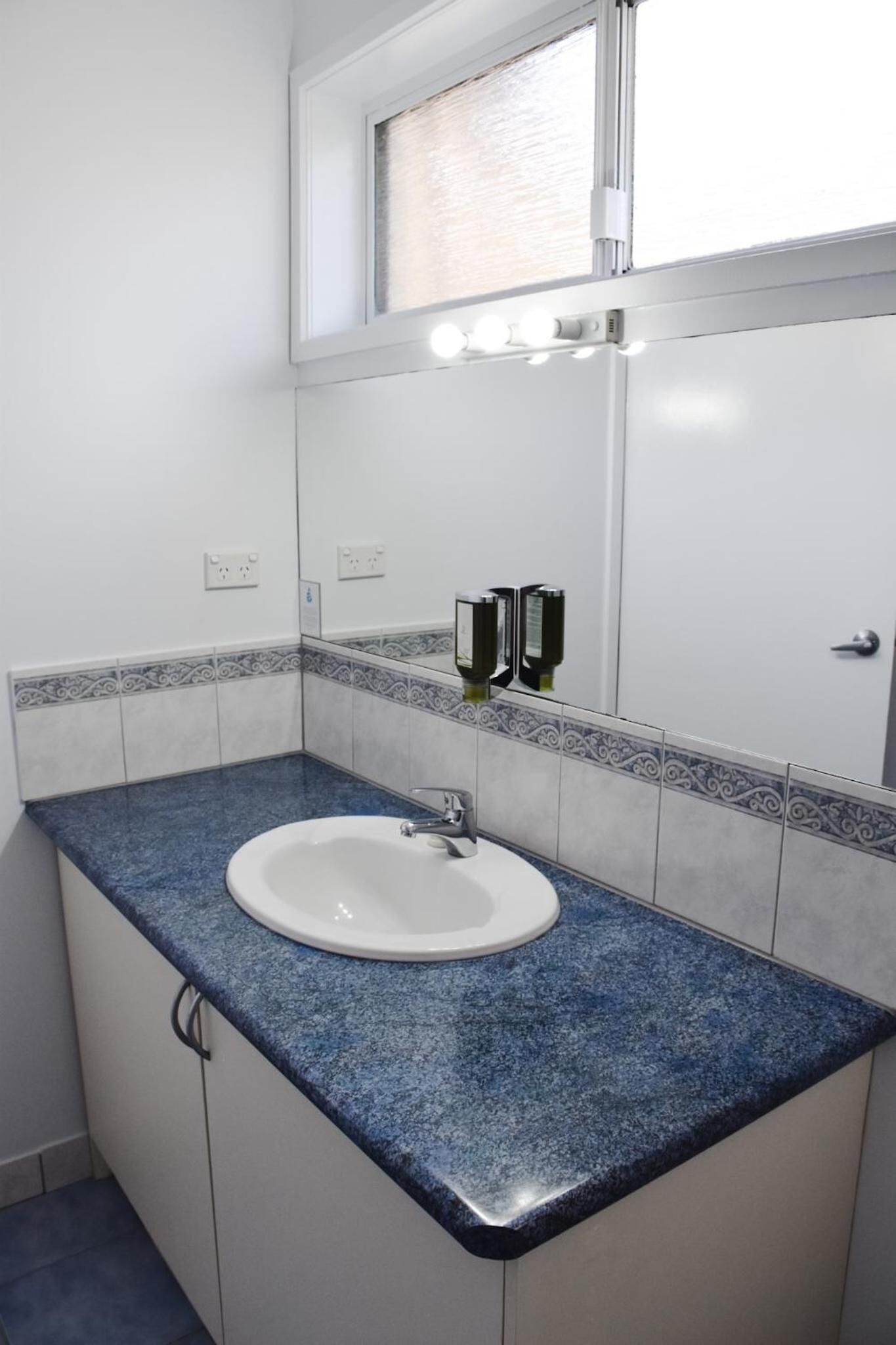 A bathroom with a white sink, blue granite countertop, and a mirror above it.