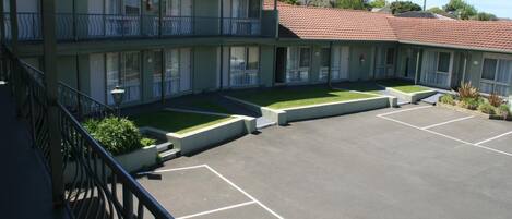 Ein Motel mit zweistöckigem Bau, einem Parkplatz und einem kleinen Garten.