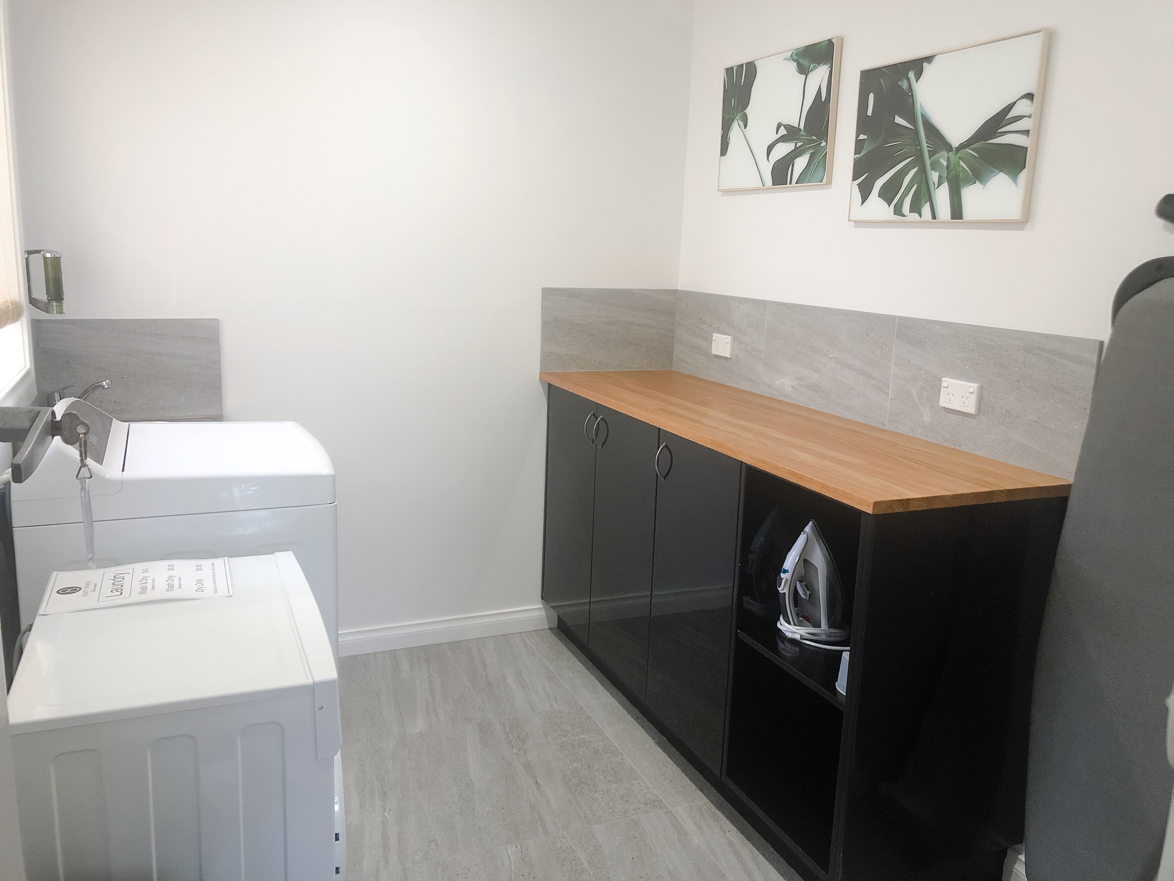 A compact kitchen with a washing machine, a drying rack, and a countertop with cabinets.