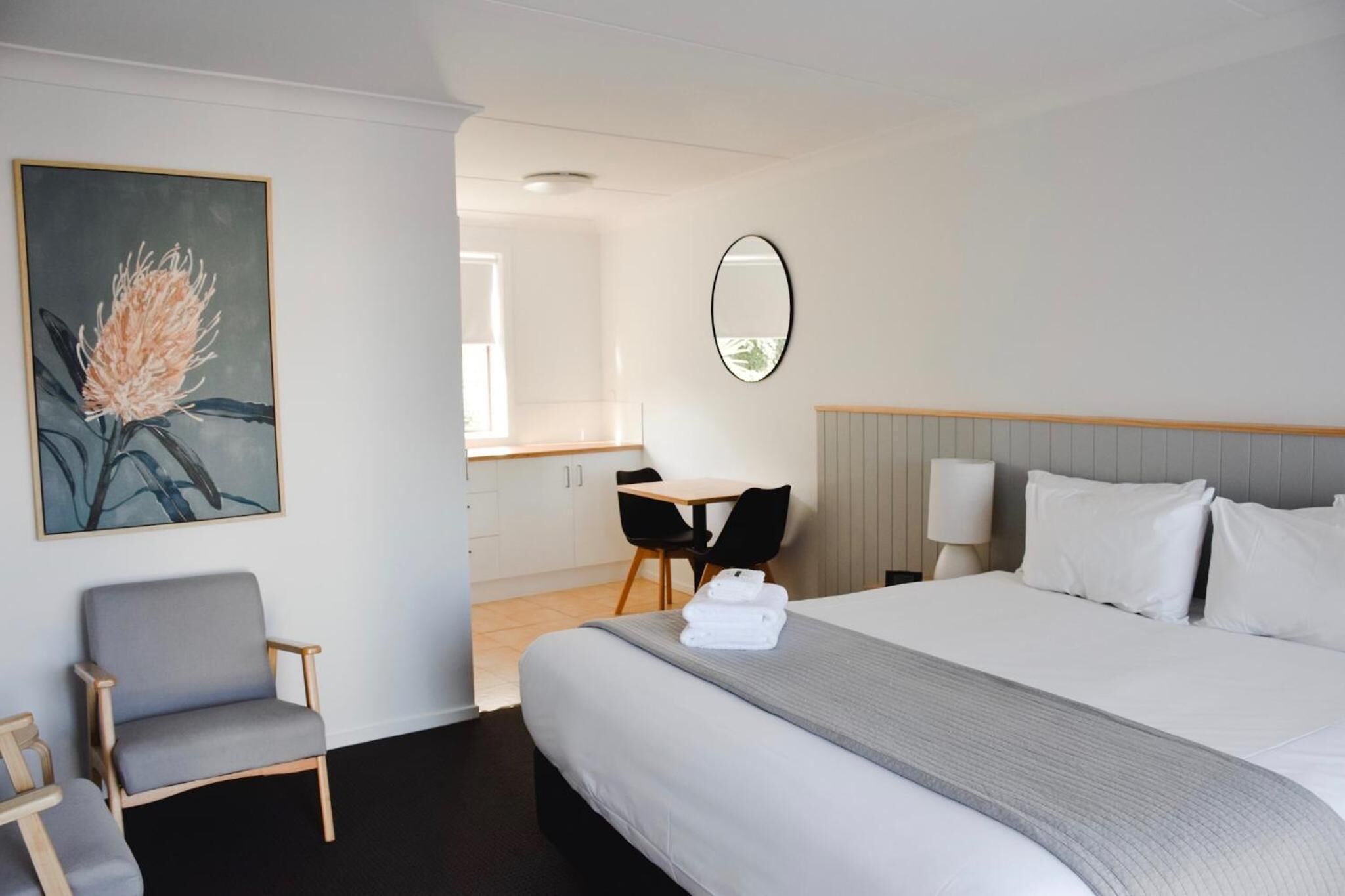 Une chambre d’hôtel avec un grand lit, un bureau, une chaise et un tableau au mur.