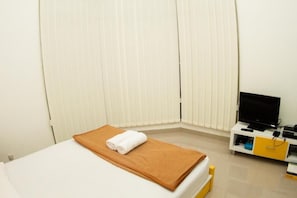 Relax in this inviting room with a comfortable bed, TV, and ample natural light.