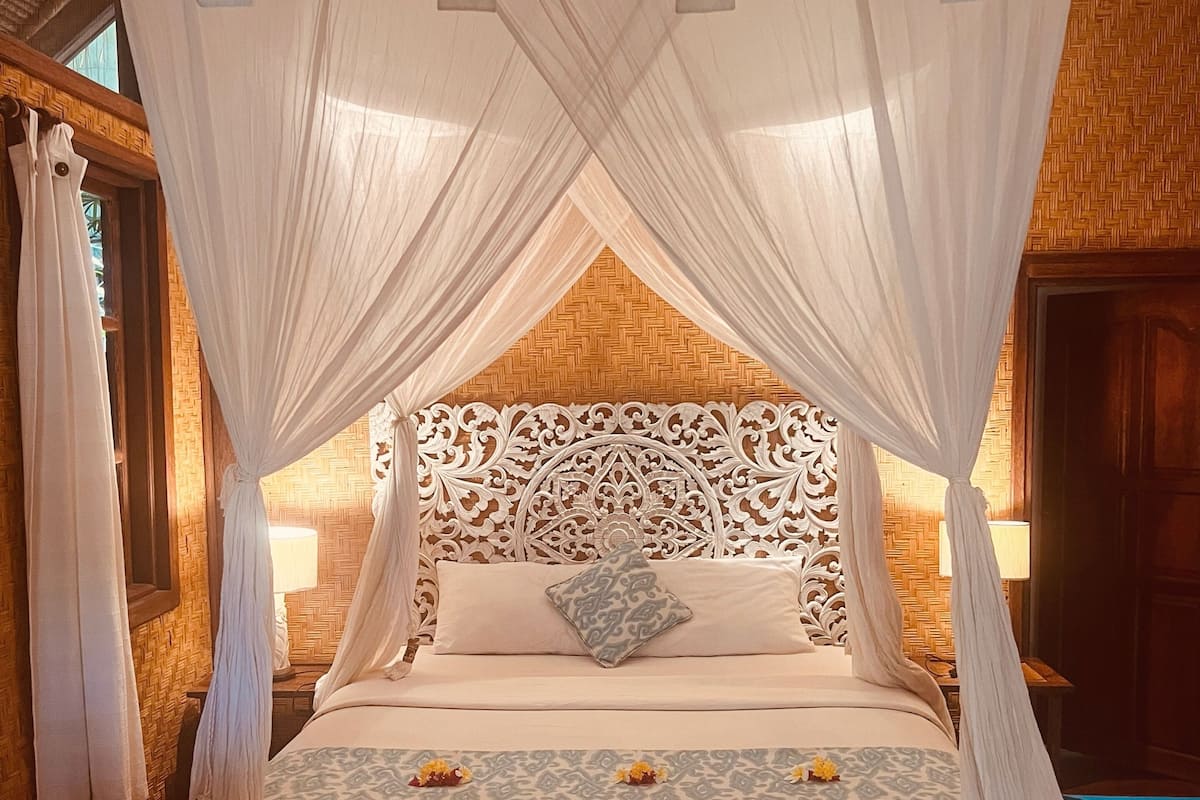 A bed with a canopy, a wooden headboard, and a patterned bedspread.
