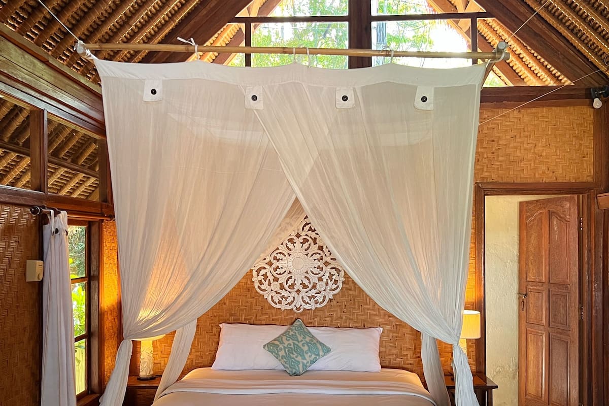 A bed with a canopy, a decorative wall hanging, and a wooden floor.
