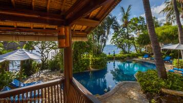 Alberca al aire libre, sombrillas en la alberca y camastros