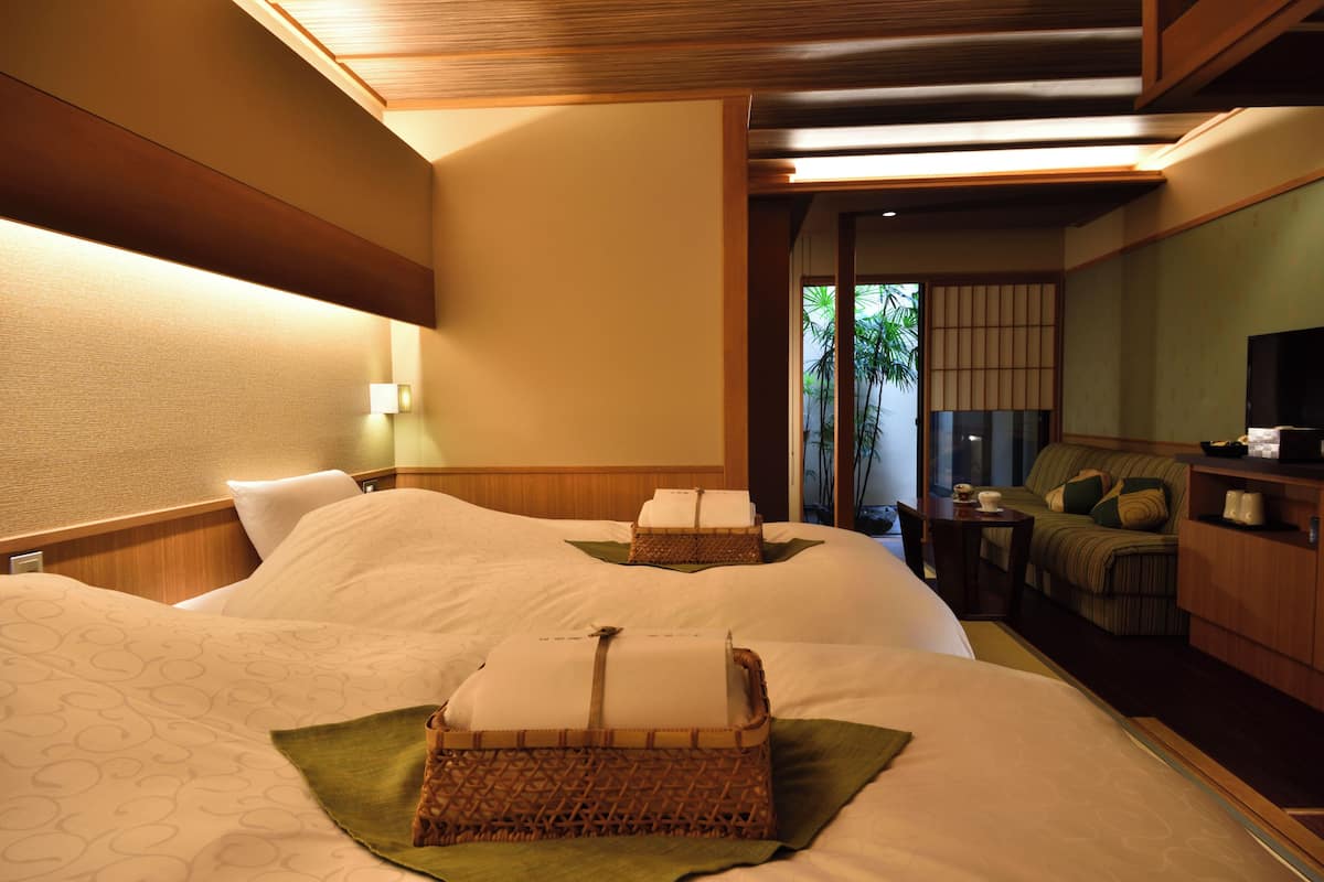 A hotel room with two beds, a sitting area, and a television.