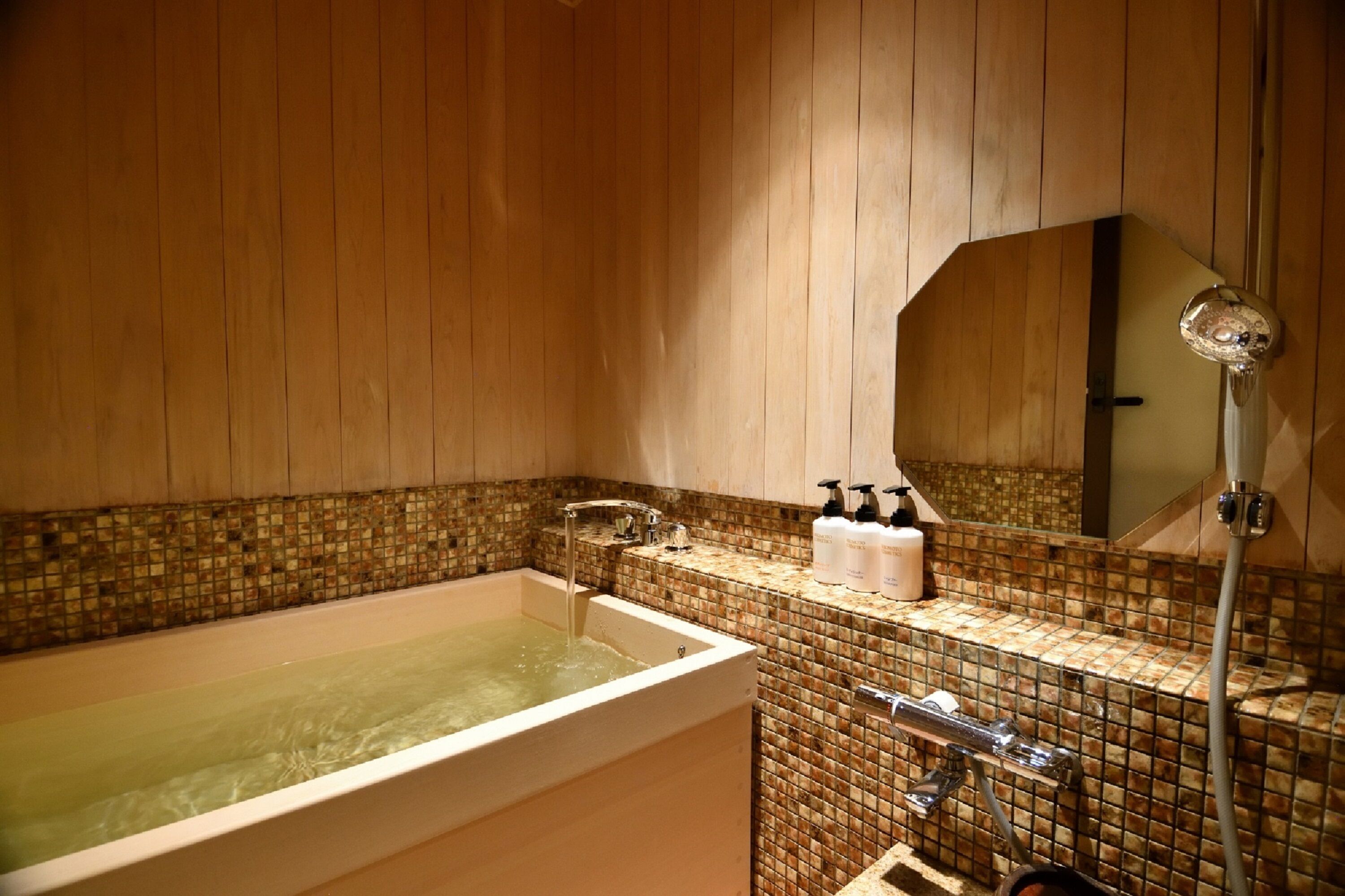 Un baño con bañera, ducha y pared de azulejos.