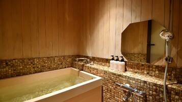 Un baño con bañera, ducha y pared de azulejos.