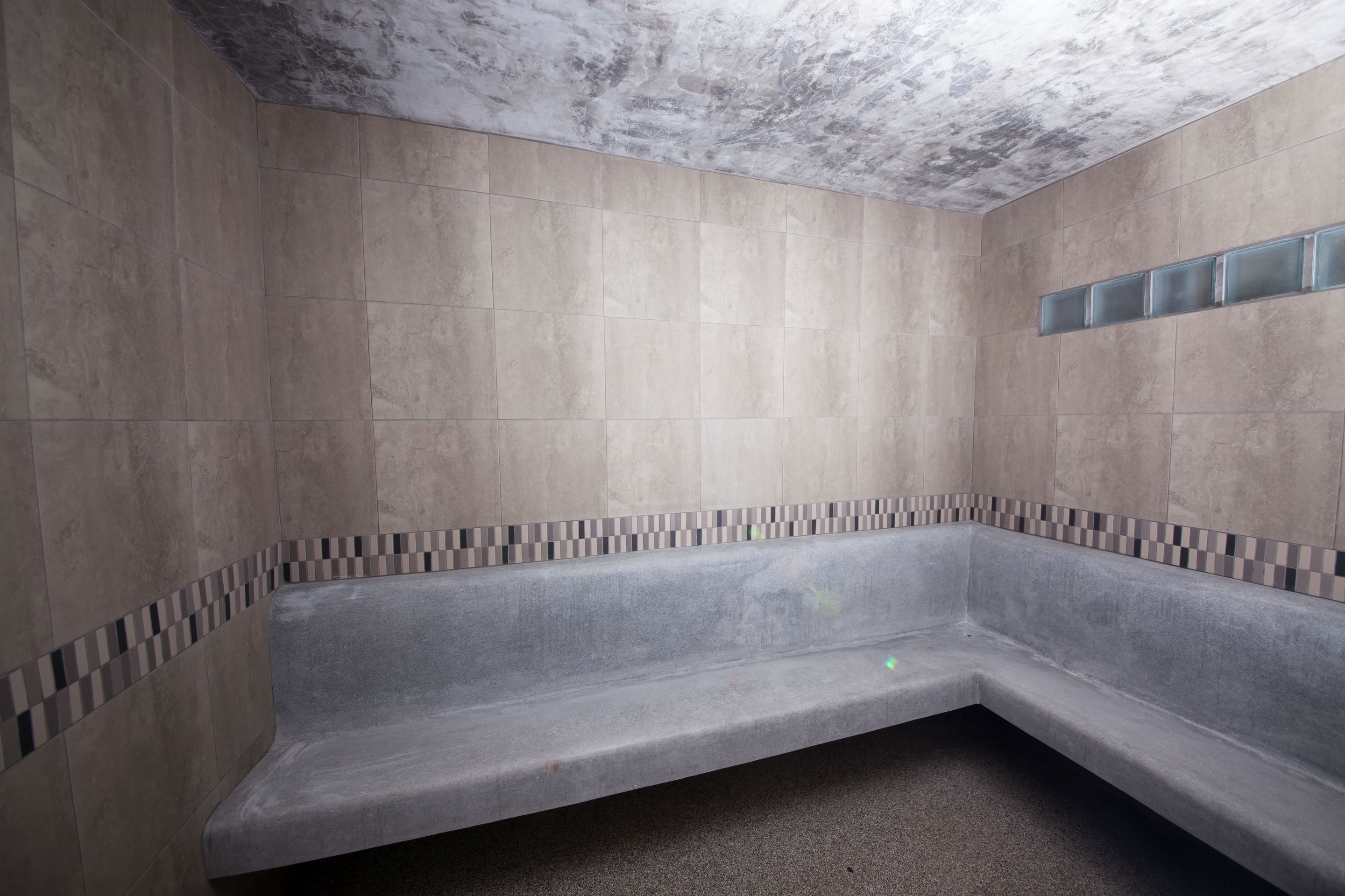 A modern bathroom with a corner bathtub, tiled walls, and a ceiling with a textured finish.