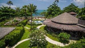 Un resort con cabañas de techo de paja, piscina y vista al mar.