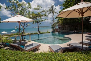 A poolside area with lounge chairs and umbrellas, overlooking a clear blue sea. - Sea Dance Resort (Koh Samui)