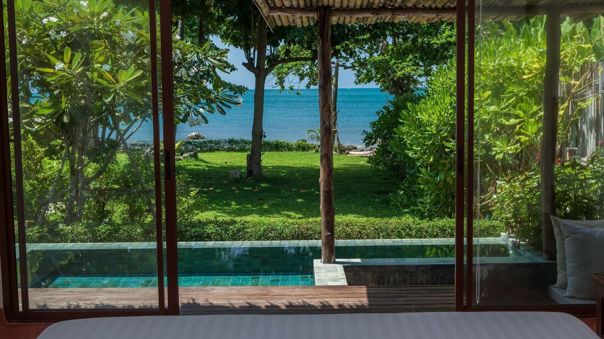 Un dormitorio con un ventanal grande que da a una piscina y vistas al mar.