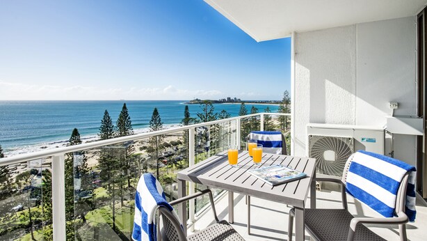 A balcony with a table, chairs, and a view of the ocean. - Pacific Beach Resort (Mooloolaba)