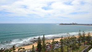 A coastal view with a beach, ocean, and parking area.