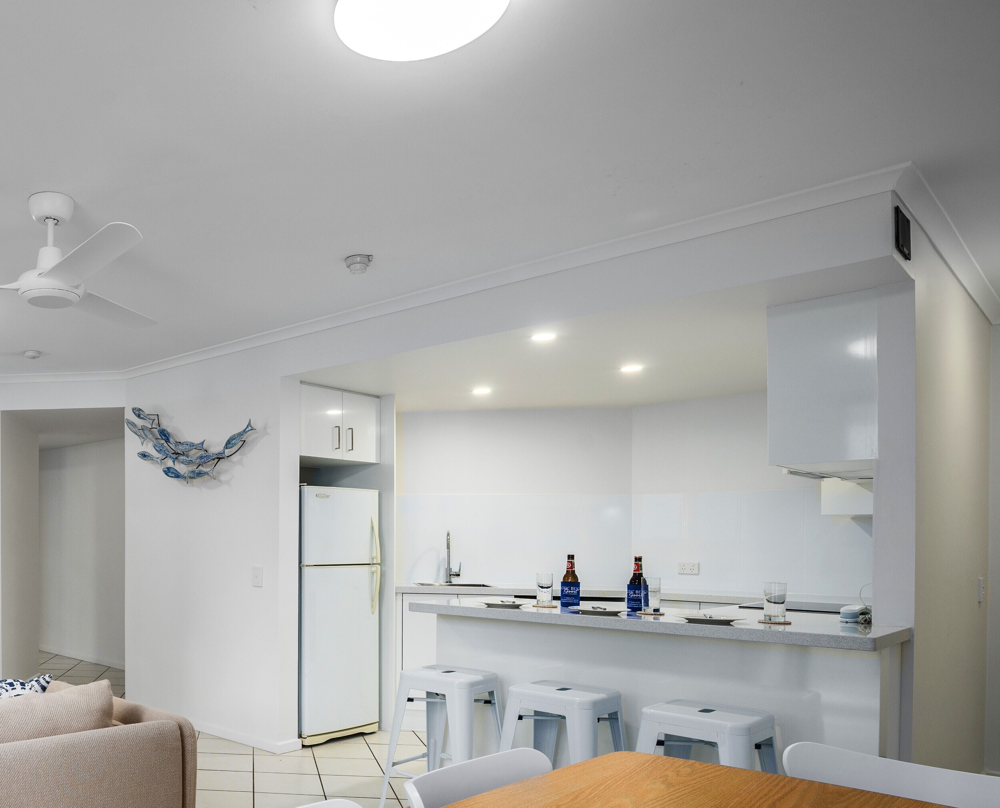 A modern kitchen with white cabinets, a built-in oven, and a countertop with two bottles and glasses.
