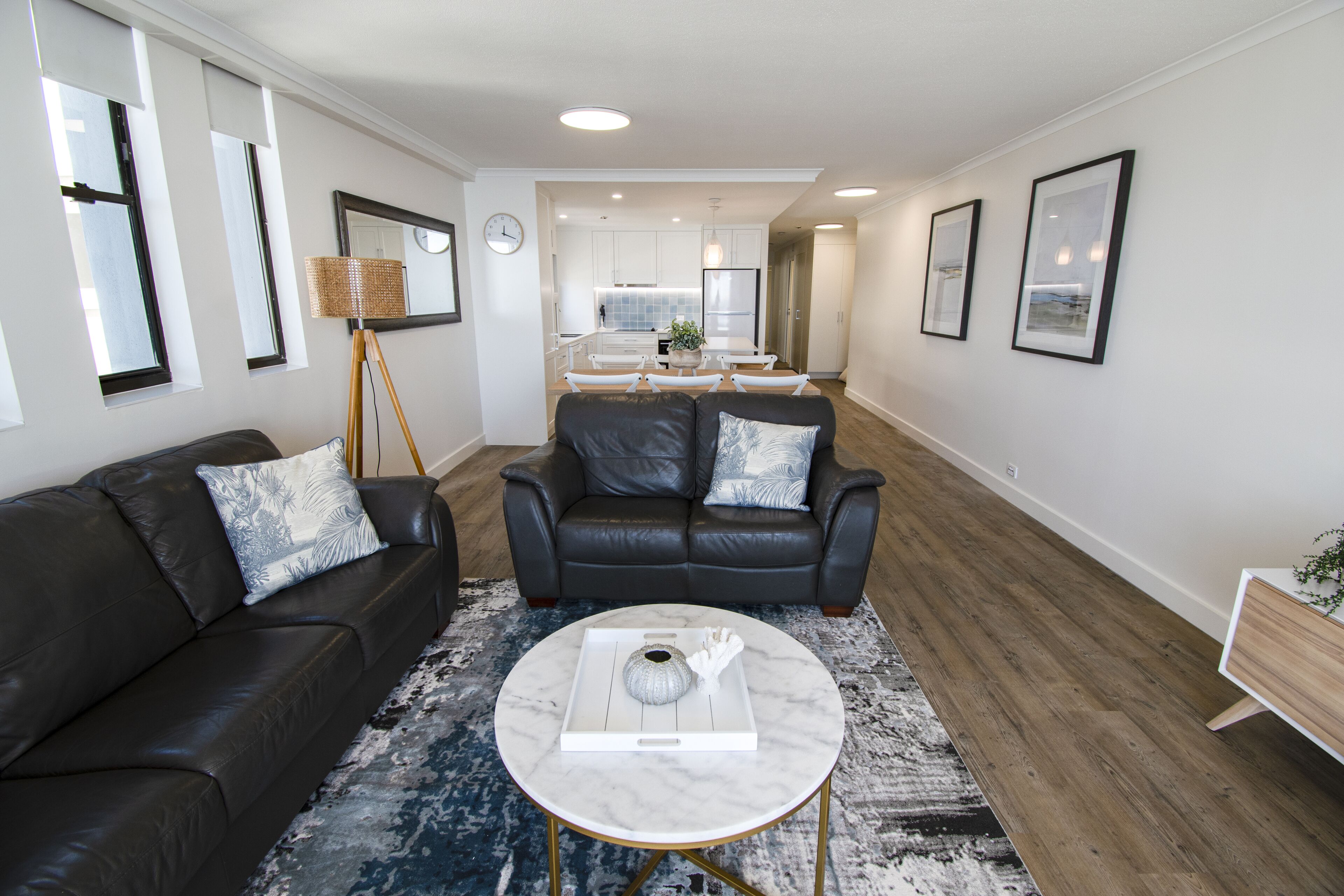 A modern living room with a black leather sofa, a round coffee table, and a patterned rug.