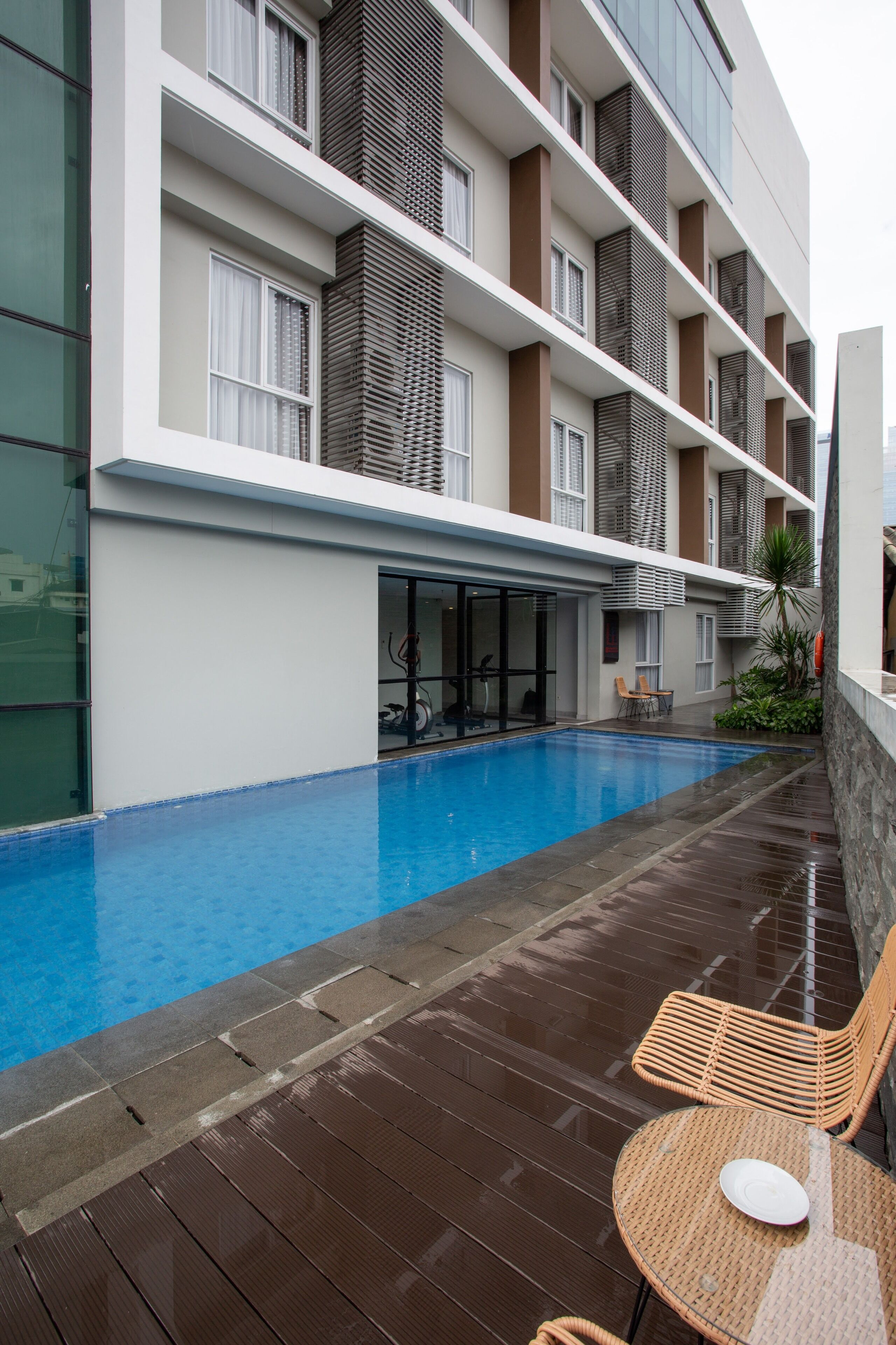 Un hôtel moderne doté d’une piscine, d’un espace extérieur aménagé et d’une zone couverte avec un mur en verre.