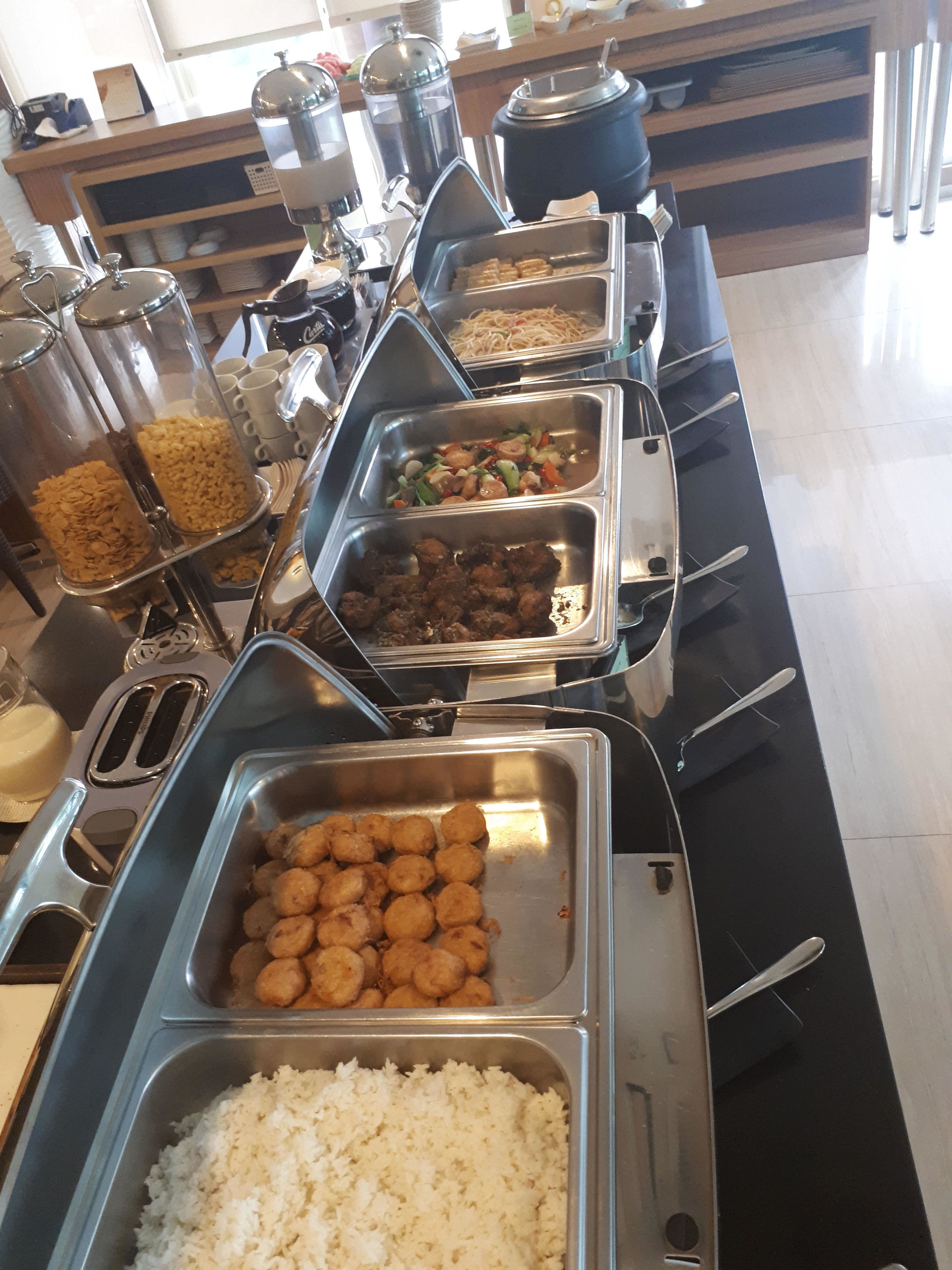 Un bufé con diversos alimentos, incluyendo arroz, albóndigas y verduras.