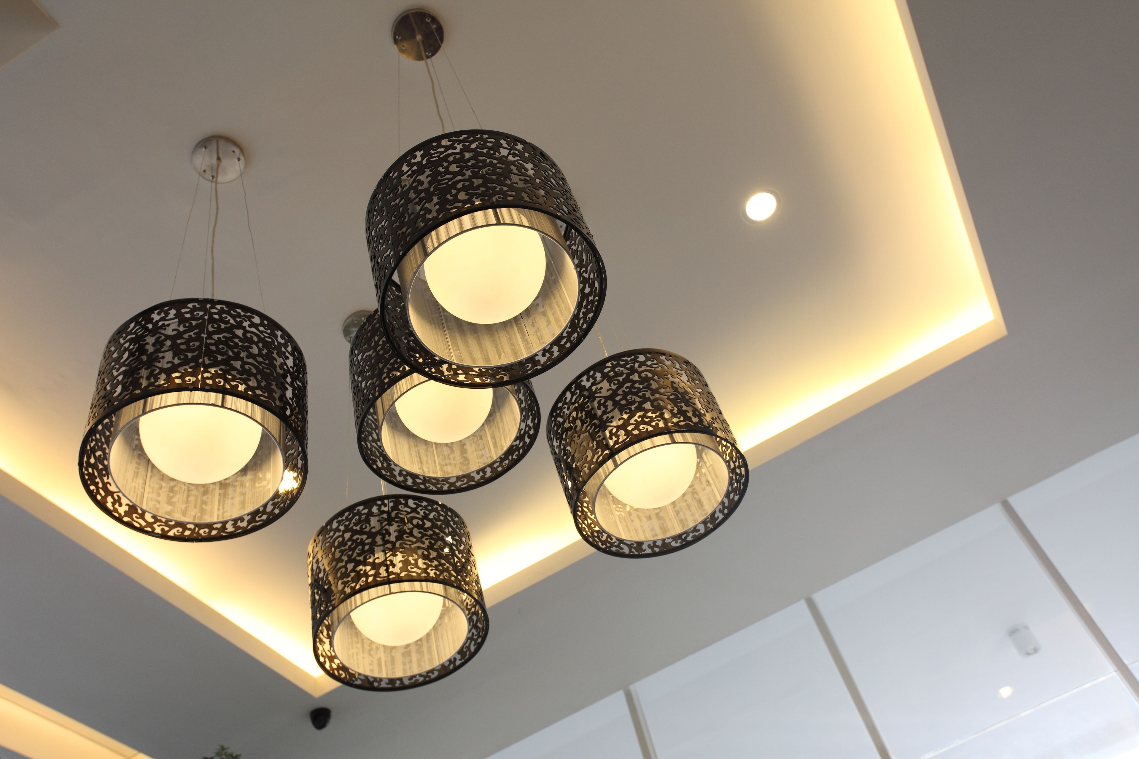 A ceiling with five cylindrical pendant lights with intricate patterns.