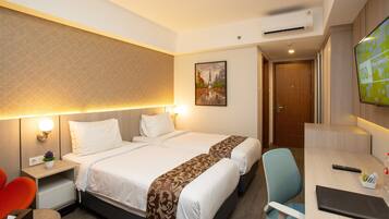 Habitación de hotel con cama, mesitas de noche, escritorio, silla, televisor y un cuadro en la pared.