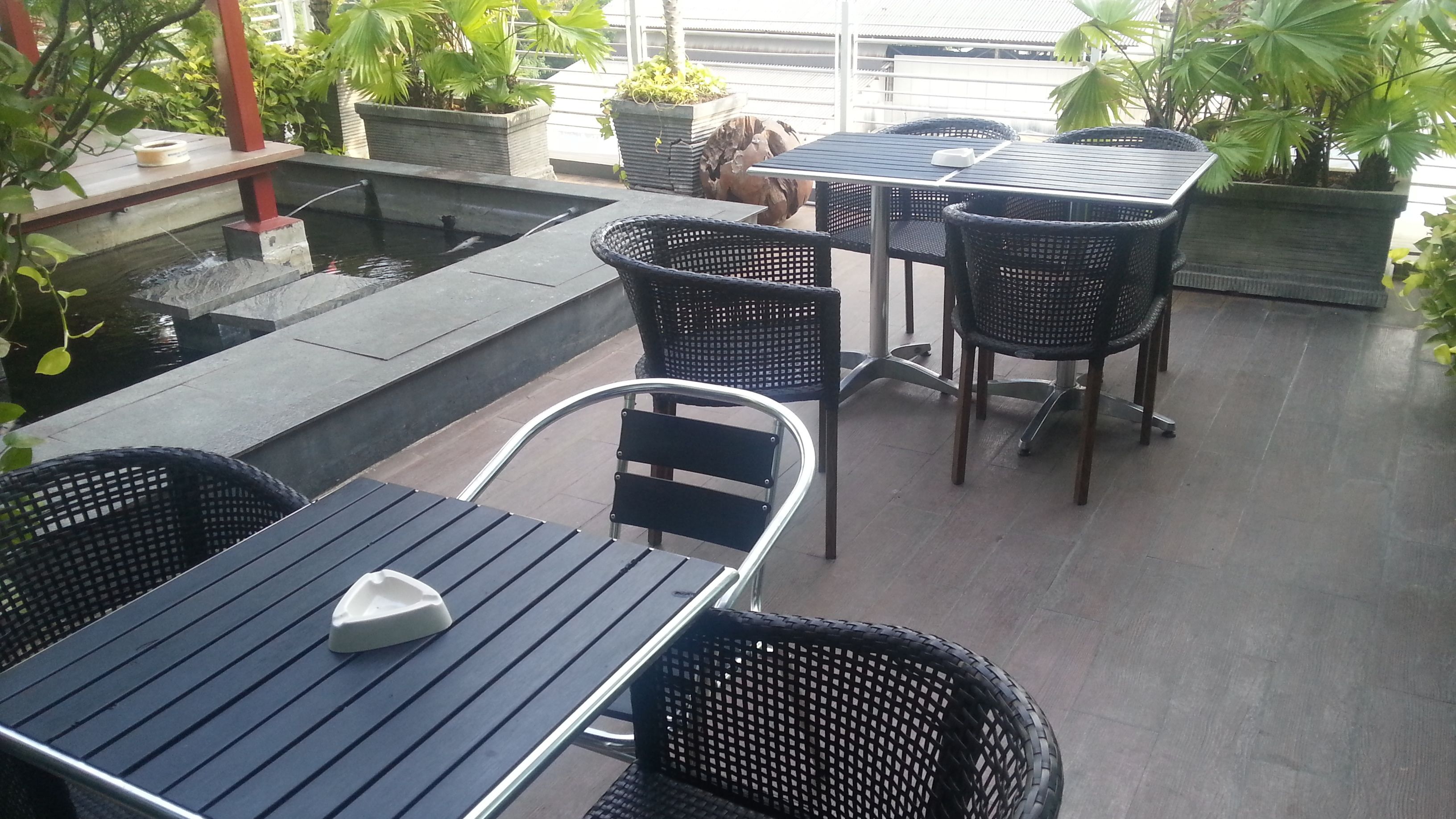 Une terrasse extérieure avec une piscine, des chaises en osier noir et une table.