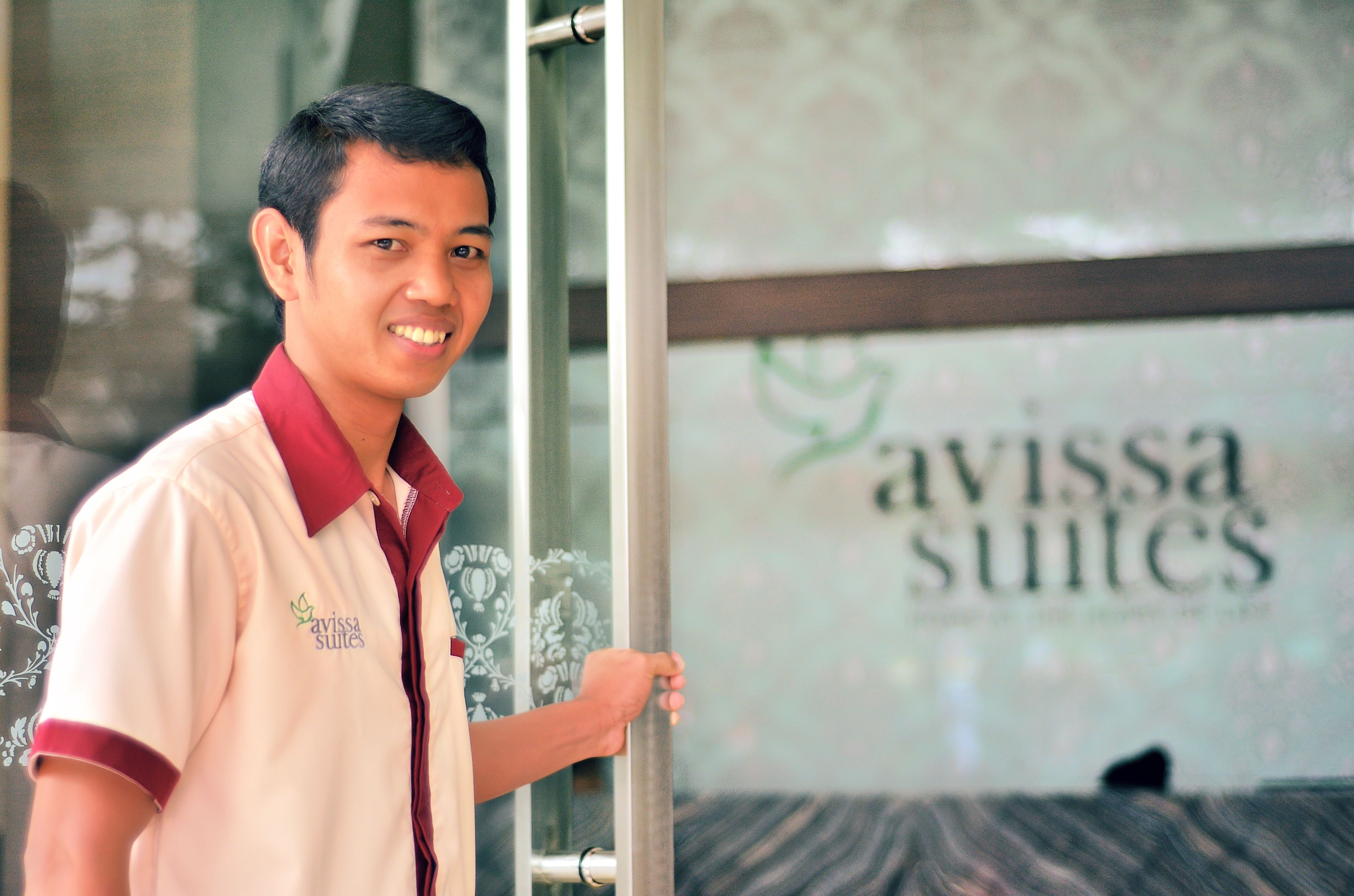 Una persona de pie frente a un puerta de vidrio con el texto "avissa suites" a la vista.