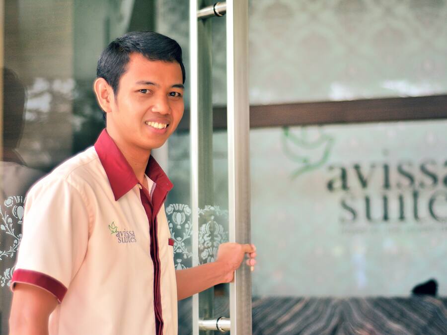 Una persona de pie frente a un puerta de vidrio con el texto "avissa suites" a la vista.