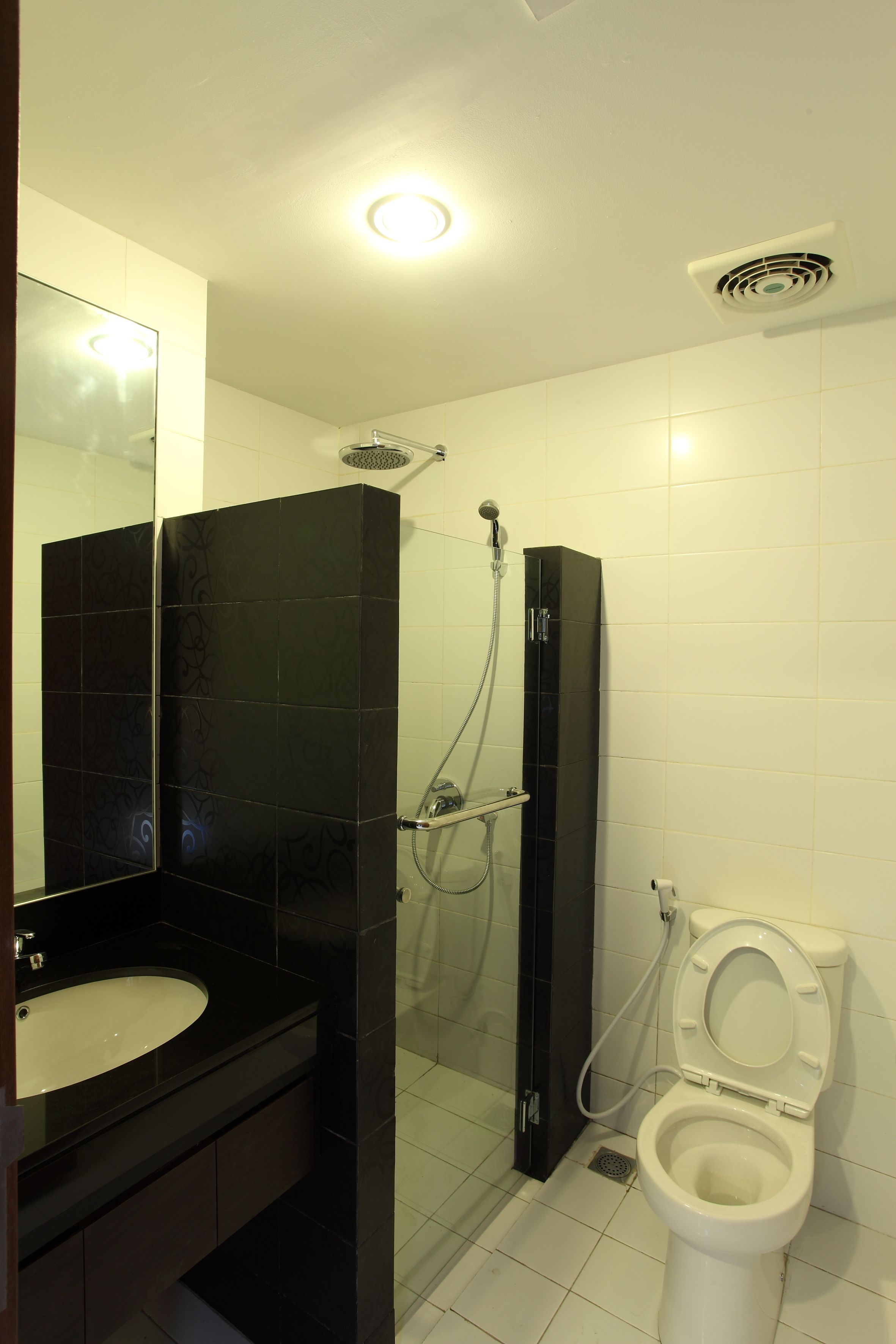 Une salle de bain avec un meuble-lavabo noir, des toilettes blanches et une douche à parois de verre.