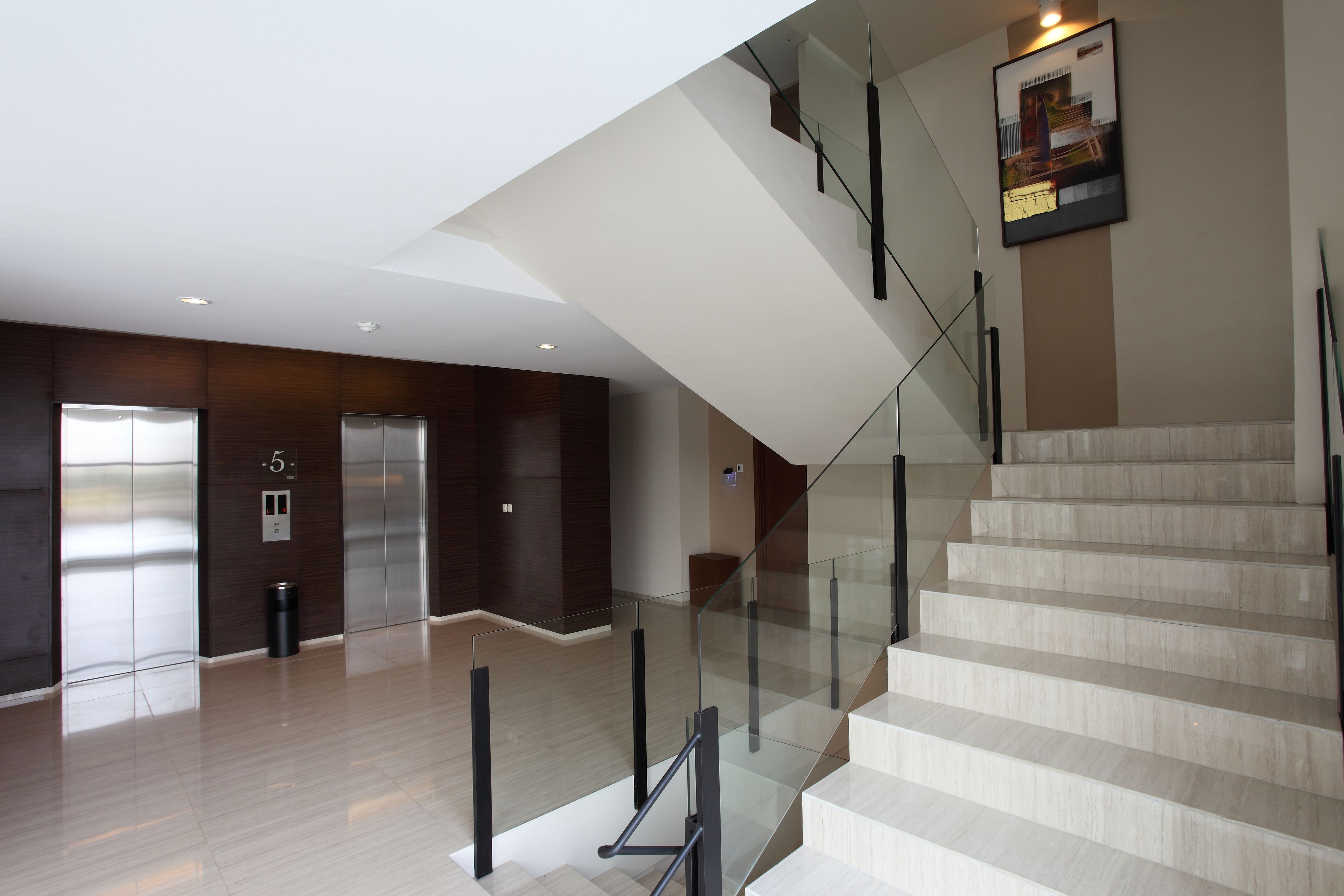 Un intérieur moderne avec un escalier, des rampes en verre et un ascenseur.