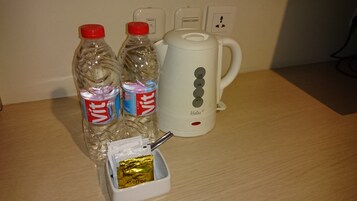 A table with two water bottles, a coffee maker, and a small container with a packet of coffee.