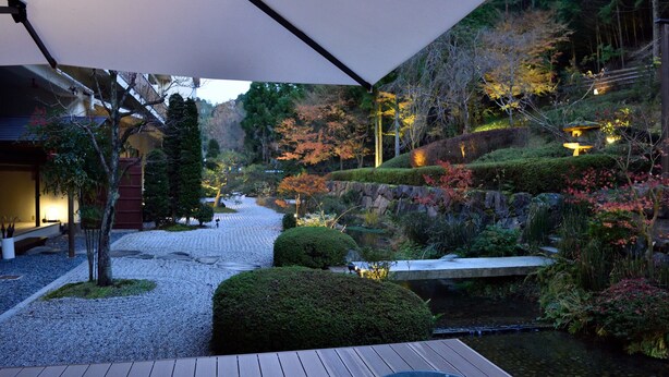 Ein friedlicher Garten mit einer Holzterrasse, einem Koiteich und einer Steinbrücke.