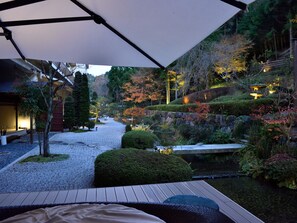 A serene garden with a wooden deck, a koi pond, and a stone bridge. - Yunohana Resort Suisen (Kameoka)