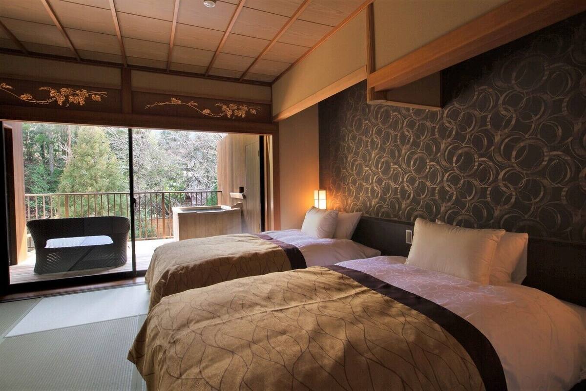 Ein Hotelzimmer mit zwei Betten, einem Balkon mit einem Stuhl und einer Wand mit Muster.