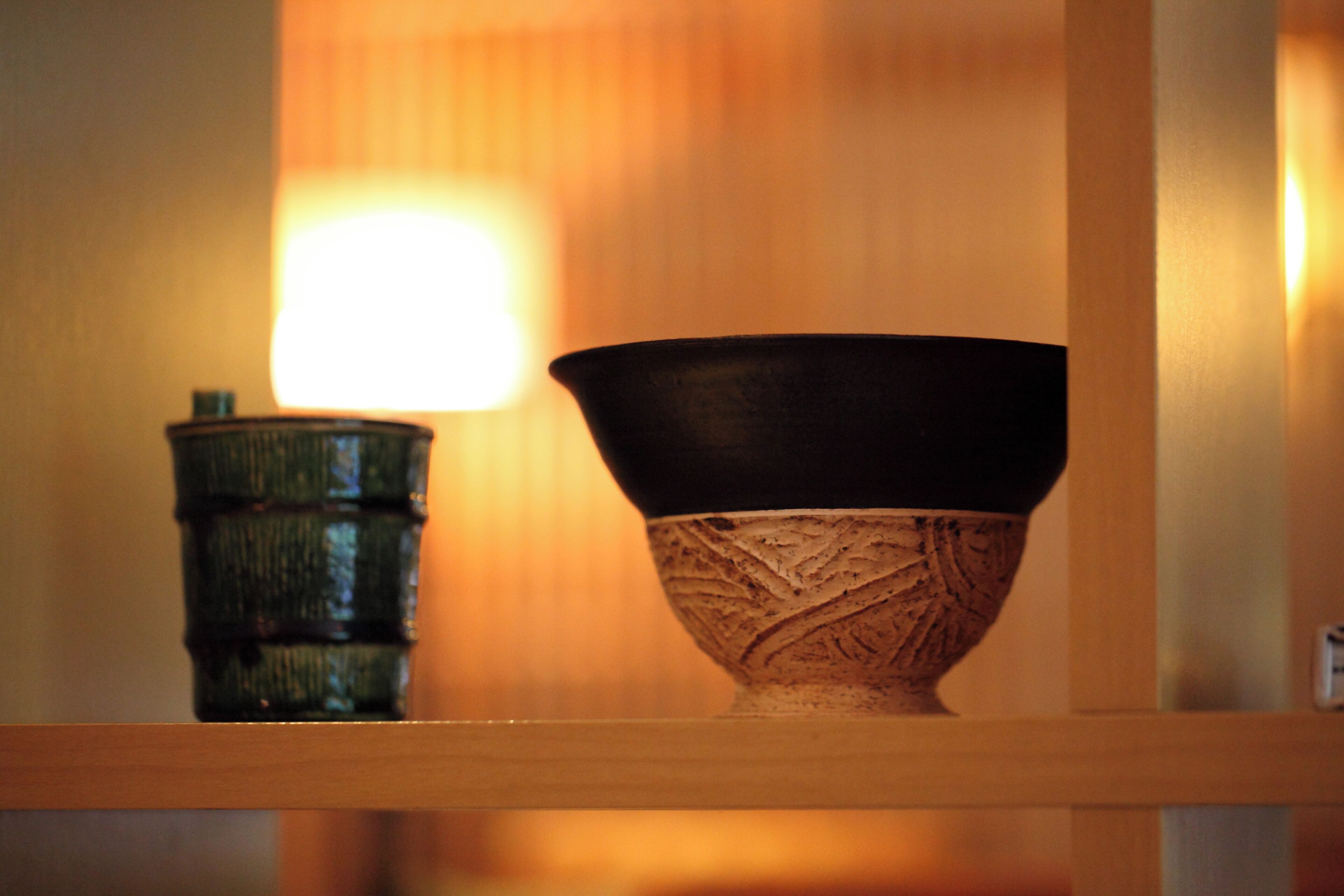 A wooden shelf with a ceramic bowl and a small container.