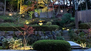 Ein traditioneller japanischer Garten mit einem Kiesweg, der zu einer Holzbauten führt.