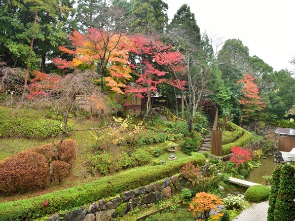 A traditional Japanese garden with stone pathways, a small pond, and various trees in autumn colors. - Yunohana Resort Suisen (Kameoka)