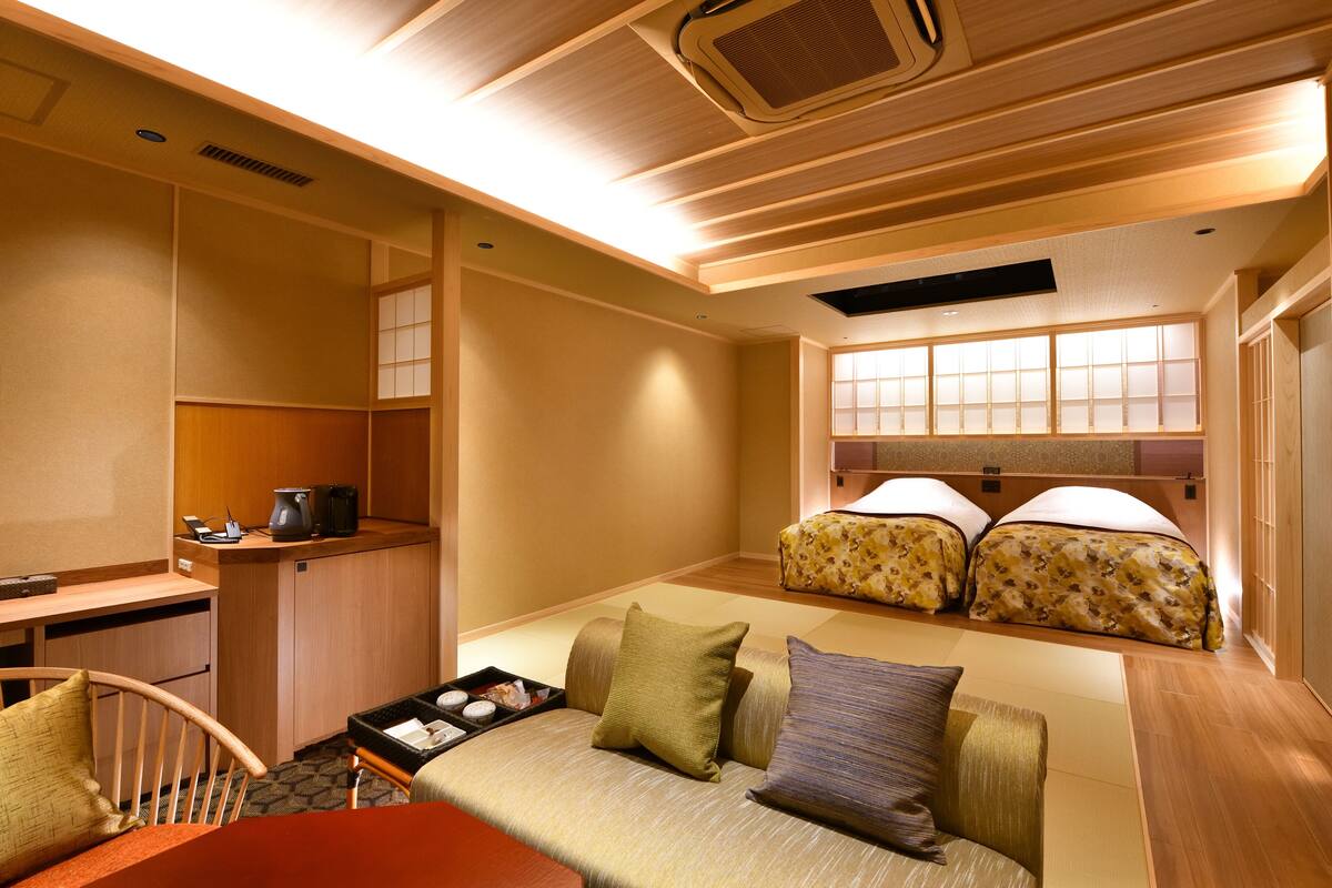 Ein kompaktes Hotelzimmer mit Küchenzeile, Schlafsofa und einer traditionellen, japanischen Schiebetür.