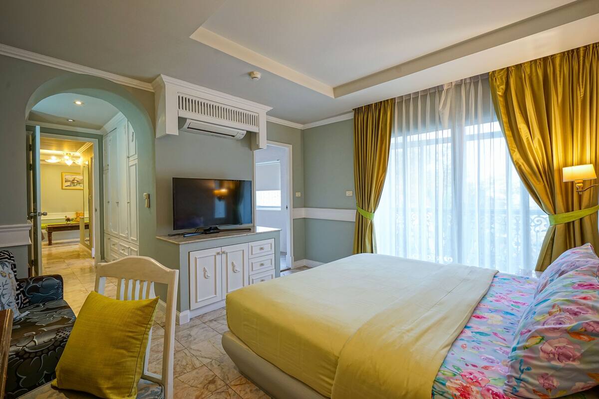 Habitació d'hotel amb llit, televisió, escriptori i cadira.
