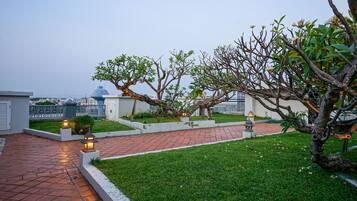 Un jardín en la azotea con senderos, árboles y faroles decorativos.