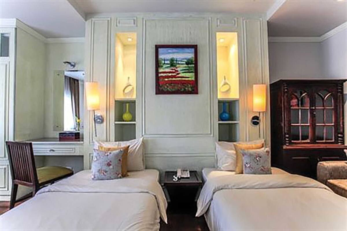 Habitació d'hotel amb dos llits, una taula, una cadira, una làmpada, un quadre i un armari.