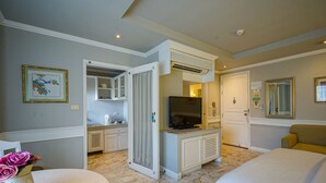 Una habitación de hotel con televisión, zona de comedor y cama.