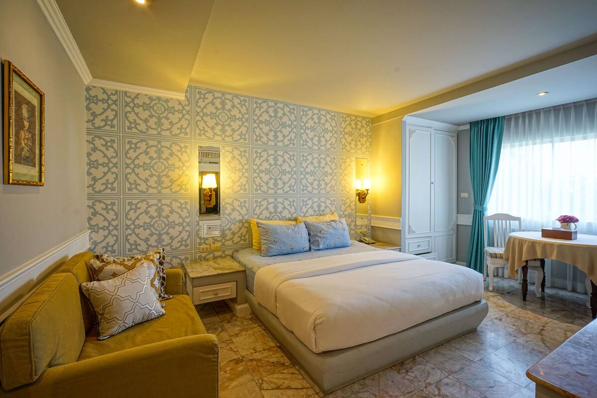 Una habitació d'hotel amb un llit gran, un sofà, un escriptori i una cadira.