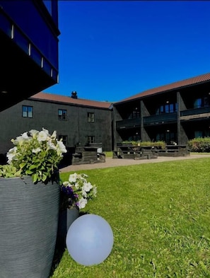 A courtyard with a building, potted plants, and a spherical object. - Oppdal Gjestetun Hotell (Oppdal)