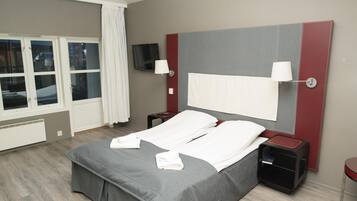 Een hotelkamer met een bed, twee nachtkastjes, een televisie en een raam met gordijnen.