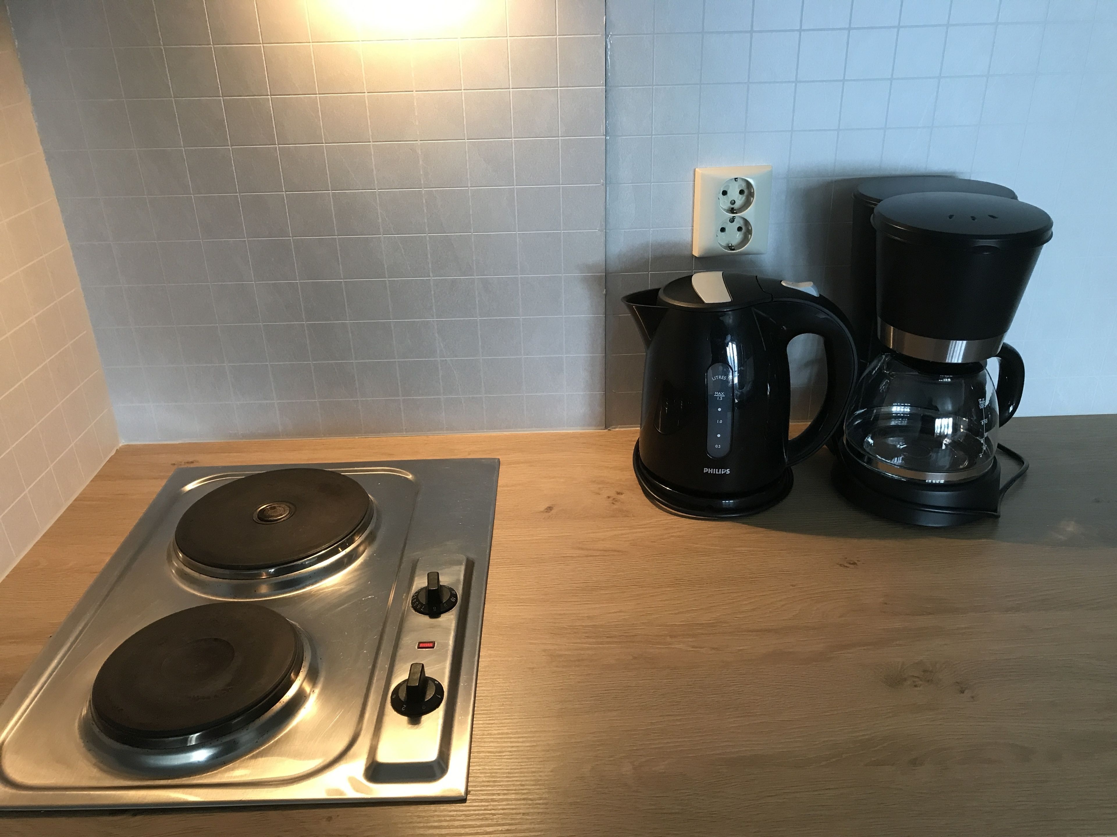Una cocina con estufa, cafetera y hervidor.