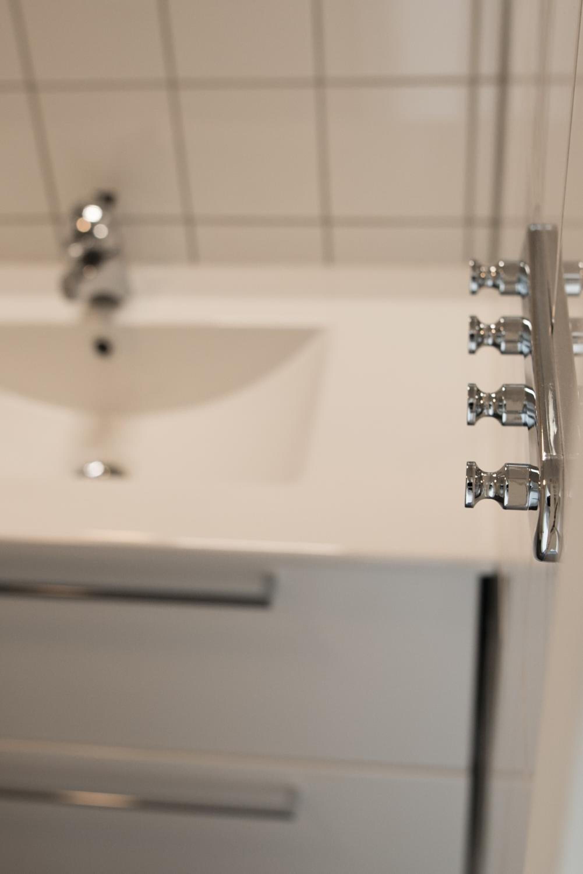 Ein Badezimmer mit einem weißen Waschbecken, einem Spiegel und einem Wasserhahn.
