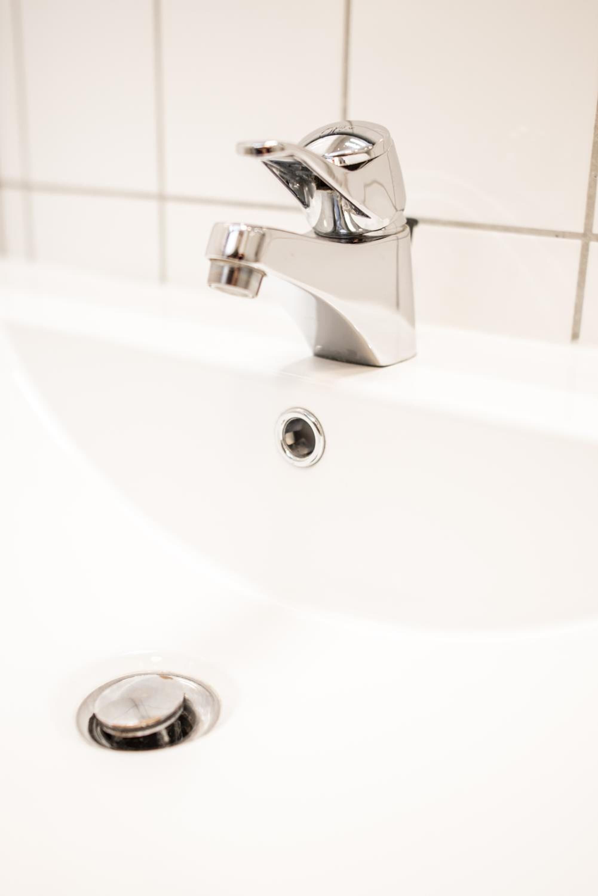 A white bathroom sink with a chrome faucet and a drain.