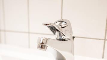 A white bathroom sink with a chrome faucet and a drain.