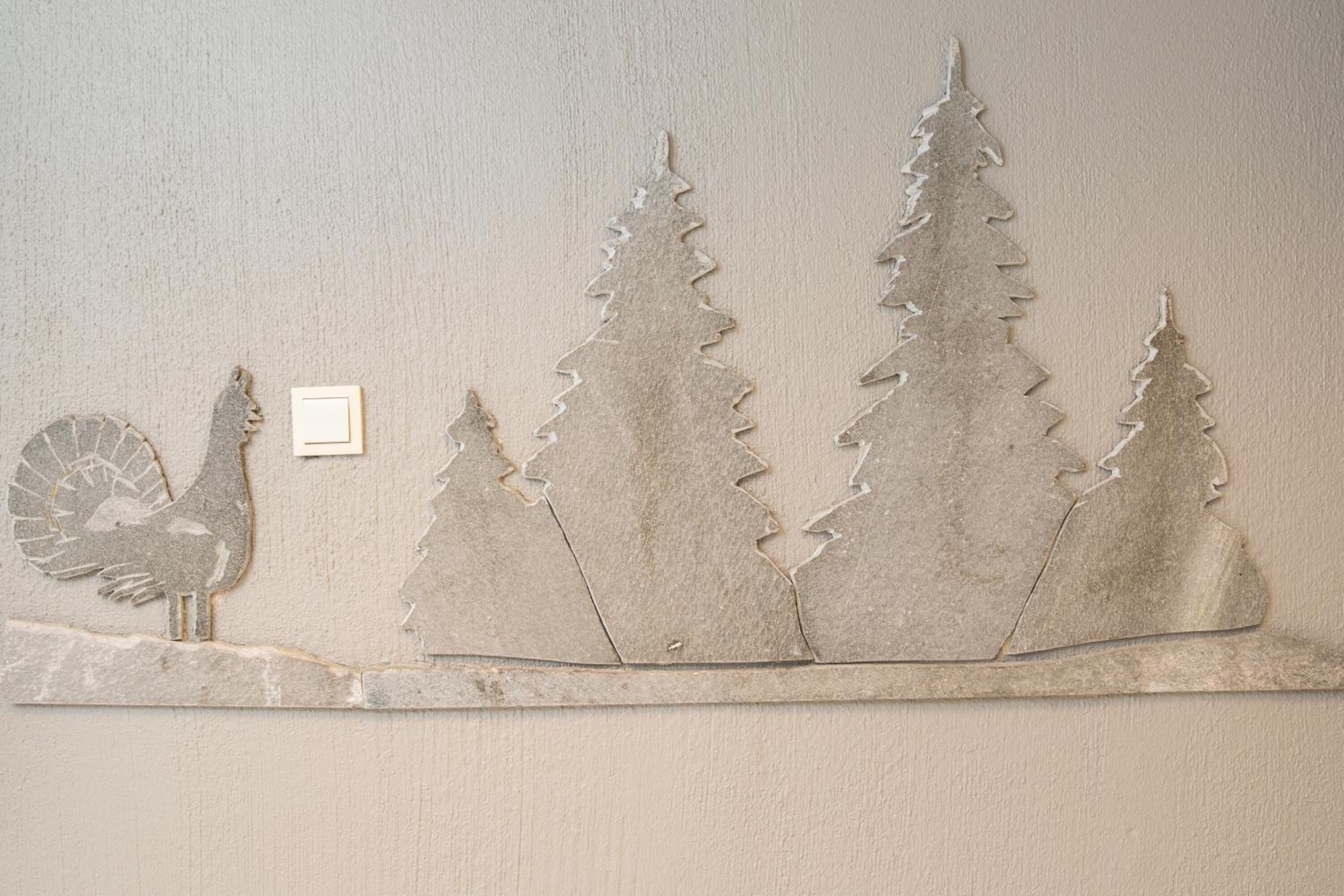Un mur orné d’une découpe décorative en métal représentant un dindon et des pins.